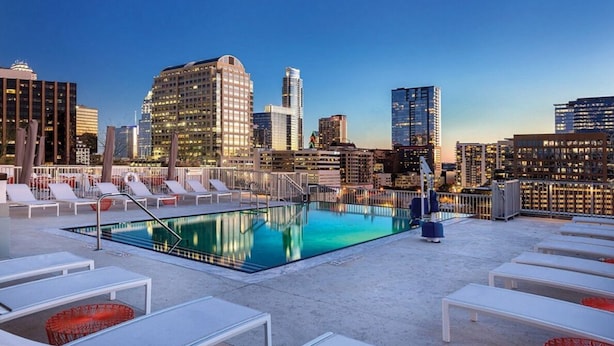Une piscine sur le toit, dotée de chaises longues et offrant une vue sur la ville.