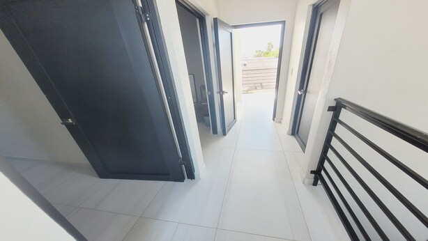 A corridor with a tiled floor, a black railing on the right, and a door on the left. - Casamar 4 by Kivoya (Puerto Peñasco)