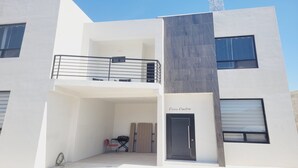 A modern building with a balcony, a door labeled "Casa Cuatro," and a small outdoor seating area with a table and chairs. - Casamar 4 by Kivoya (Puerto Peñasco)