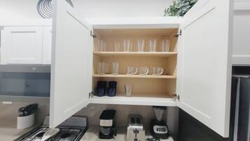 Une cuisine équipée d’un meuble intégré contenant de la vaisselle, une machine à café, un grille-pain et un mixeur.