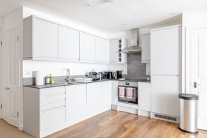A modern kitchen with white cabinetry, a stainless steel sink, and a built-in oven.