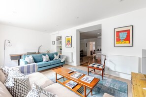 Un salon moderne comprenant un canapé, une table basse et un coin repas avec des chaises.