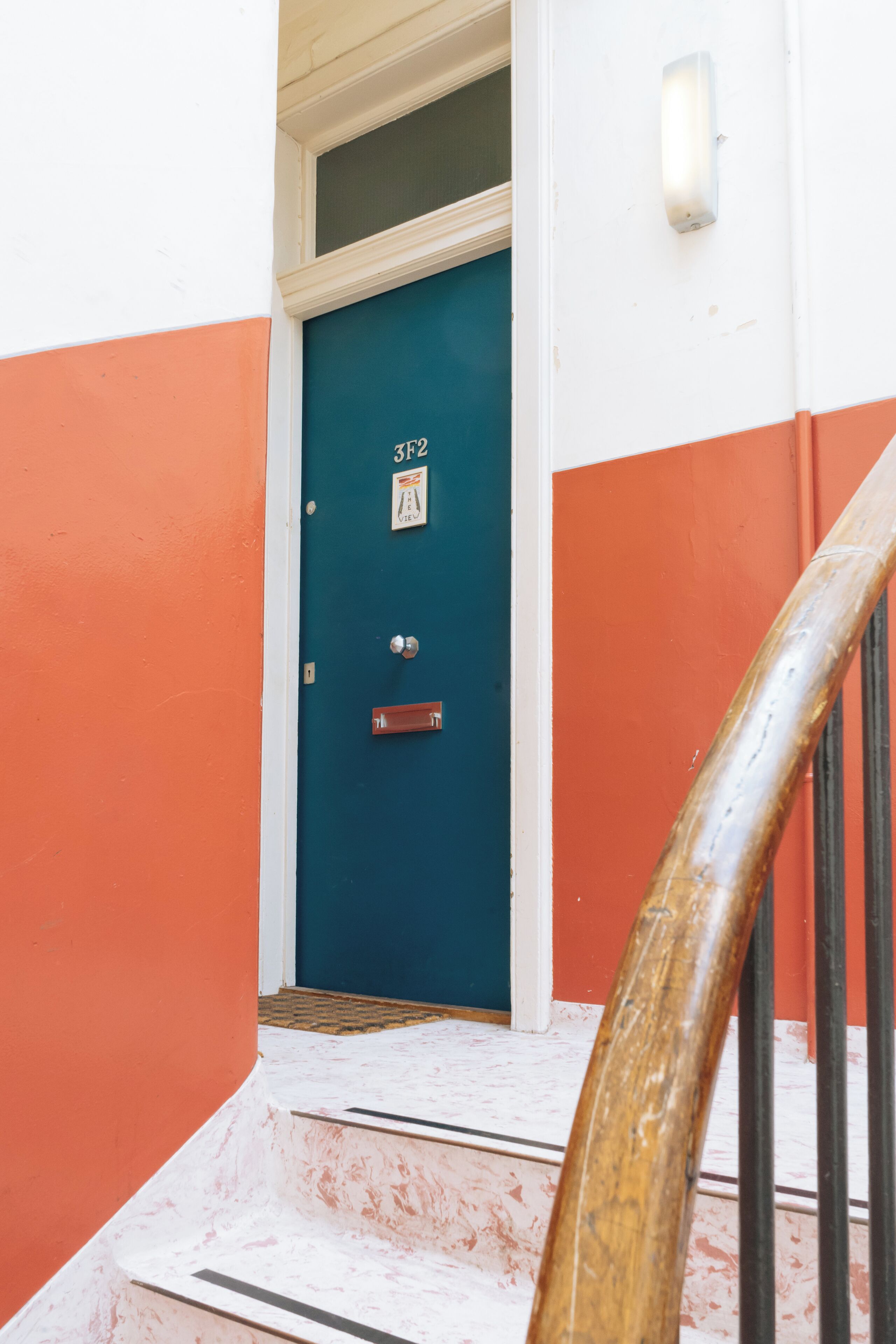 Sininen ovi, jossa on numerokilpi, metallinen kahva ja pieni kyltti sen yläpuolella.