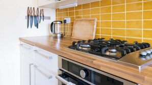 A kitchen with a gas stove, wooden countertop, and a set of knives hanging on the wall. - Stylish 1BD Flat - Abbeyhill (Edinburgh)