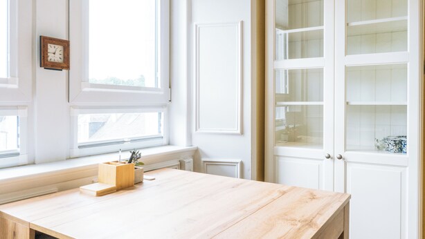 A room with a wooden table, a clock on the wall, and a window with a view of the outside. - Stylish 1BD Flat - Abbeyhill (Edinburgh)