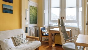A cozy living room with a sofa, chairs, a table, and a large window with a view. - Stylish 1BD Flat - Abbeyhill (Edinburgh)