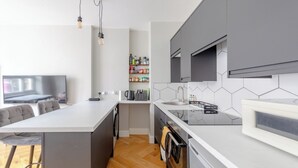 Moderni keittiö, jossa on keskeinen keittiösaareke, harmaat kaapit, mikroaaltouuni ja sisäänrakennettu uuni.