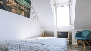 Une chambre à coucher avec un lit, une télévision, une chaise et une fenêtre.