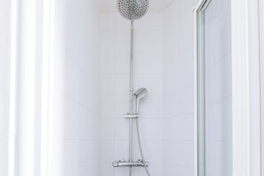 A shower with a handheld showerhead and a fixed showerhead, both mounted on a wall. - Bright and Central Studio Apartment for 2, Paris (Paris)
