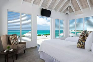 A bedroom with a large bed, a chair, and a TV on the ceiling.