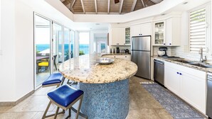 Una cocina moderna con una isla central, horno integrado y un refrigerador grande.