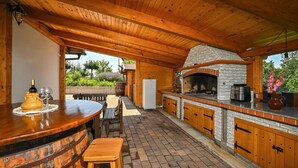 An outdoor kitchen with a brick oven, wooden bar, and seating area. - Pet friendly home in Veliki Lovrecan with sauna (Veliki Lovrecan)