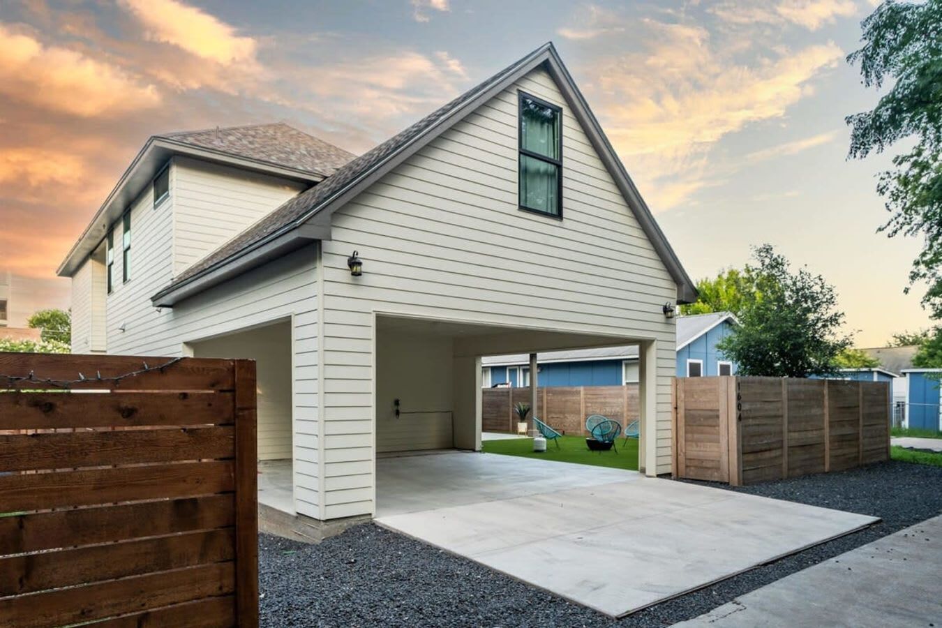 A two-story house with a covered garage and a fenced backyard.