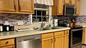 A modern kitchen with wooden cabinets, stainless steel appliances, and a tiled backsplash. - Mountain View Stay LLC -  The perfect place to get away, relax and enjoy nature. (Mena)