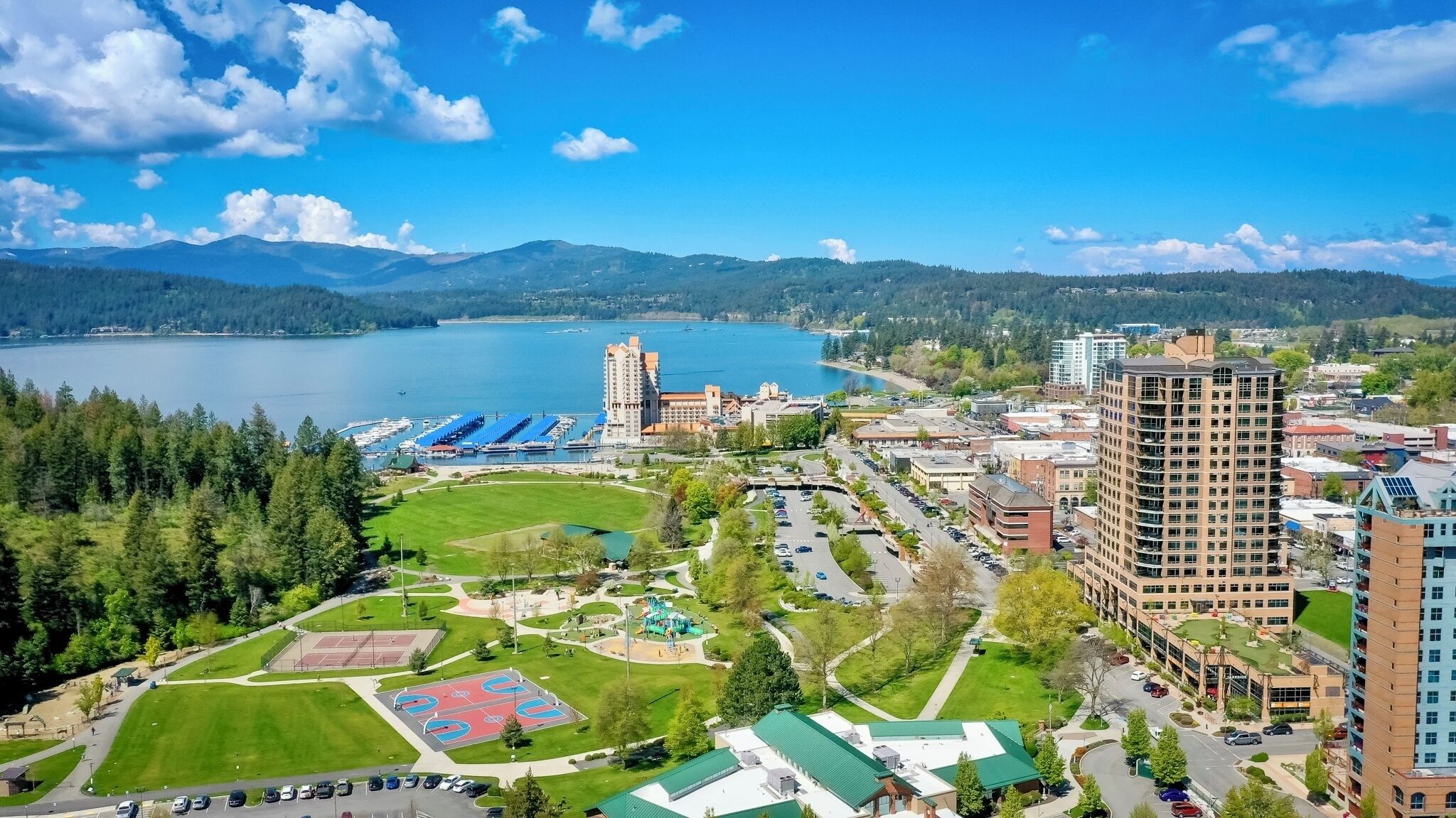 Paisagem urbana costeira com um porto de iates, instalações esportivas e edifícios modernos.