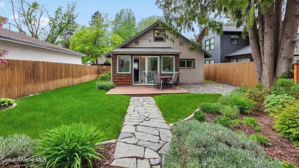 Une maison de plain-pied avec un chemin de pierre menant à un patio aménagé avec du mobilier d’extérieur.