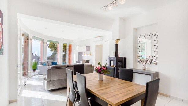 Un comedor moderno con una mesa de madera y sillas negras, una chimenea y vistas al exterior.