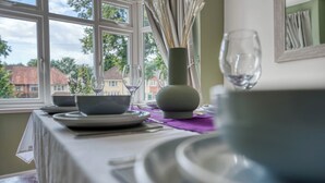 A dining table set with plates, bowls, and a vase with dried flowers. - Charming 4 Bedroom Birmingham Home (Birmingham)