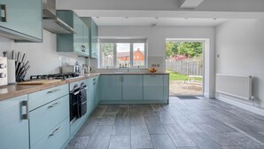 A modern kitchen with light blue cabinets, a wooden countertop, and a view to the outside. - Charming 4 Bedroom Birmingham Home (Birmingham)