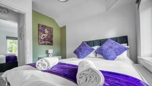 A hotel room with a bed, purple pillows, a Buddha painting, and a purple throw blanket. - Charming 4 Bedroom Birmingham Home (Birmingham)