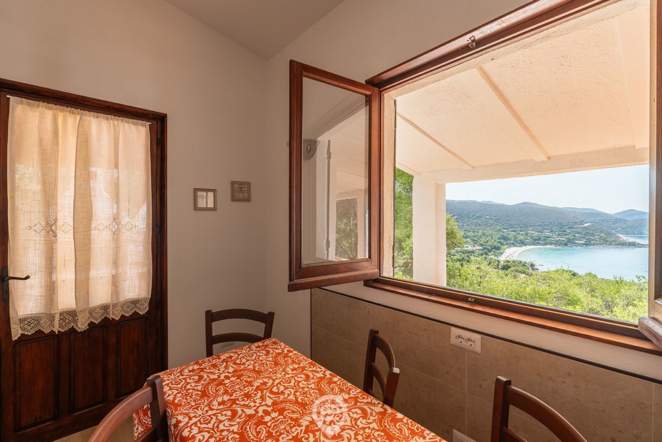 Una habitación con una mesa y sillas, una ventana que ofrece vistas a un paisaje y una puerta con cortina.