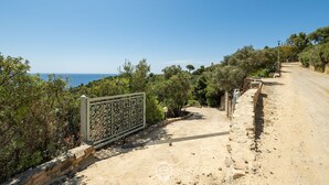 Ein unbefestigter Weg führt zu einem Tor mit Blick auf das Meer.