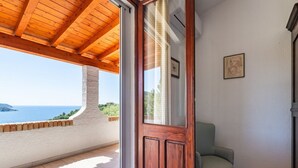Ein Balkon mit Holzboden, Blick auf das Meer und ein Stuhl.