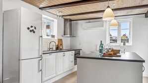 A modern kitchen with white cabinets, a central island, and a large window providing natural light.