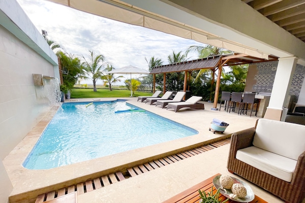 Una piscina al aire libre, sombrillas, sillones reclinables de piscina