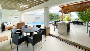 A covered outdoor area with a pool, seating, and a bar.