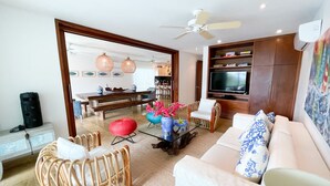 A modern living room with a sofa, chairs, a coffee table, and a TV.