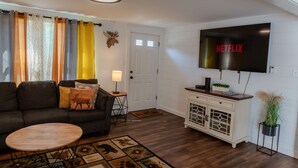 A living room with a sofa, coffee table, and a TV mounted on the wall. - Deer Ridge A/C, Firepit, Pool Table, Acadia (Ellsworth)