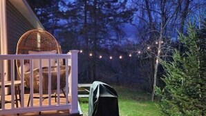 A wooden deck with a white railing, a wicker chair, and a covered object. - Deer Ridge A/C, Firepit, Pool Table, Acadia (Ellsworth)