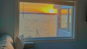 A room with a large window overlooking a sunset over water. - Water View home Minutes to all Acadia NP Sites! (Trenton)