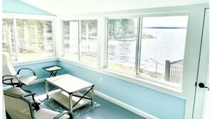 A sunroom with a view of the water, a table, and chairs. - Water View home Minutes to all Acadia NP Sites! (Trenton)