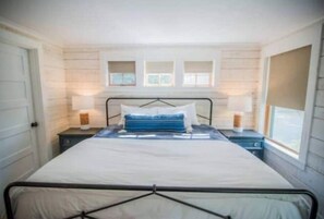A bedroom with a bed, bedside tables, and a window.