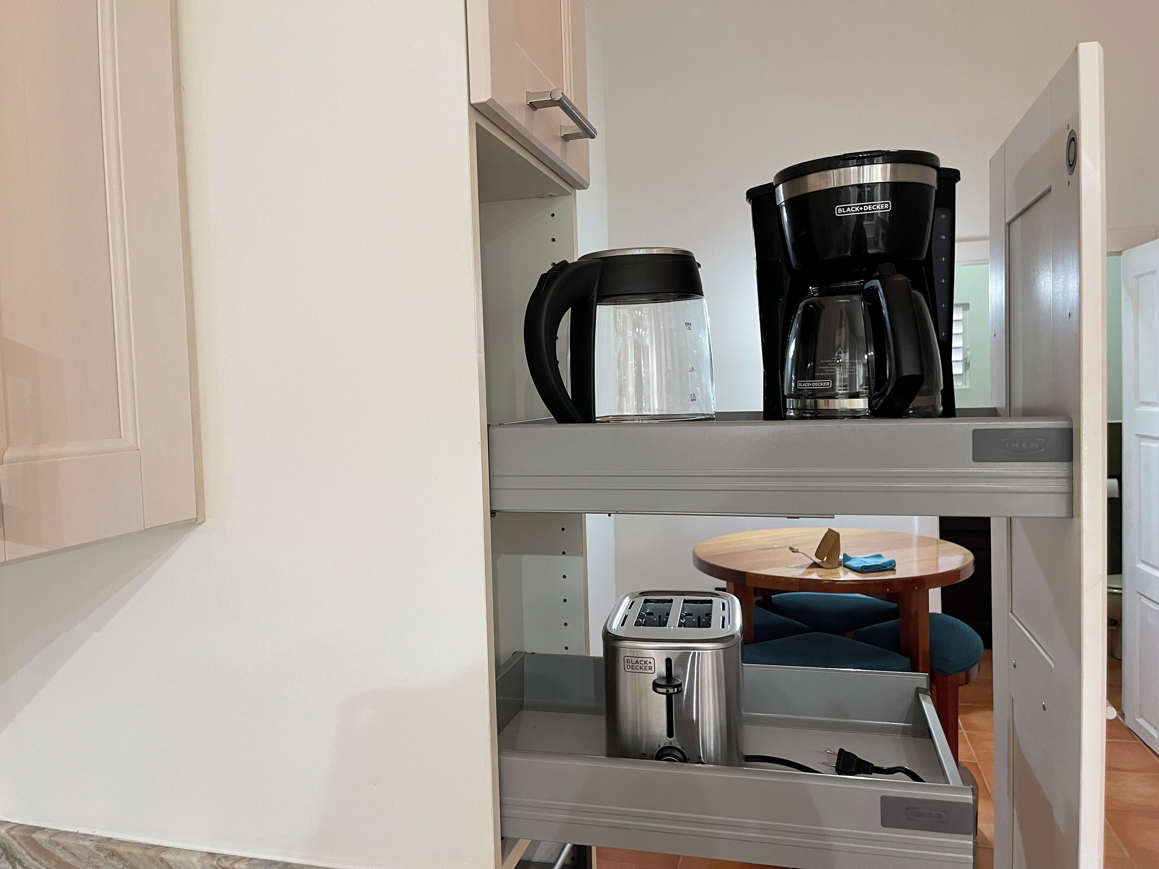 Une petite cuisine équipée d’une machine à café, d’un grille-pain et d’une petite table avec une chaise.