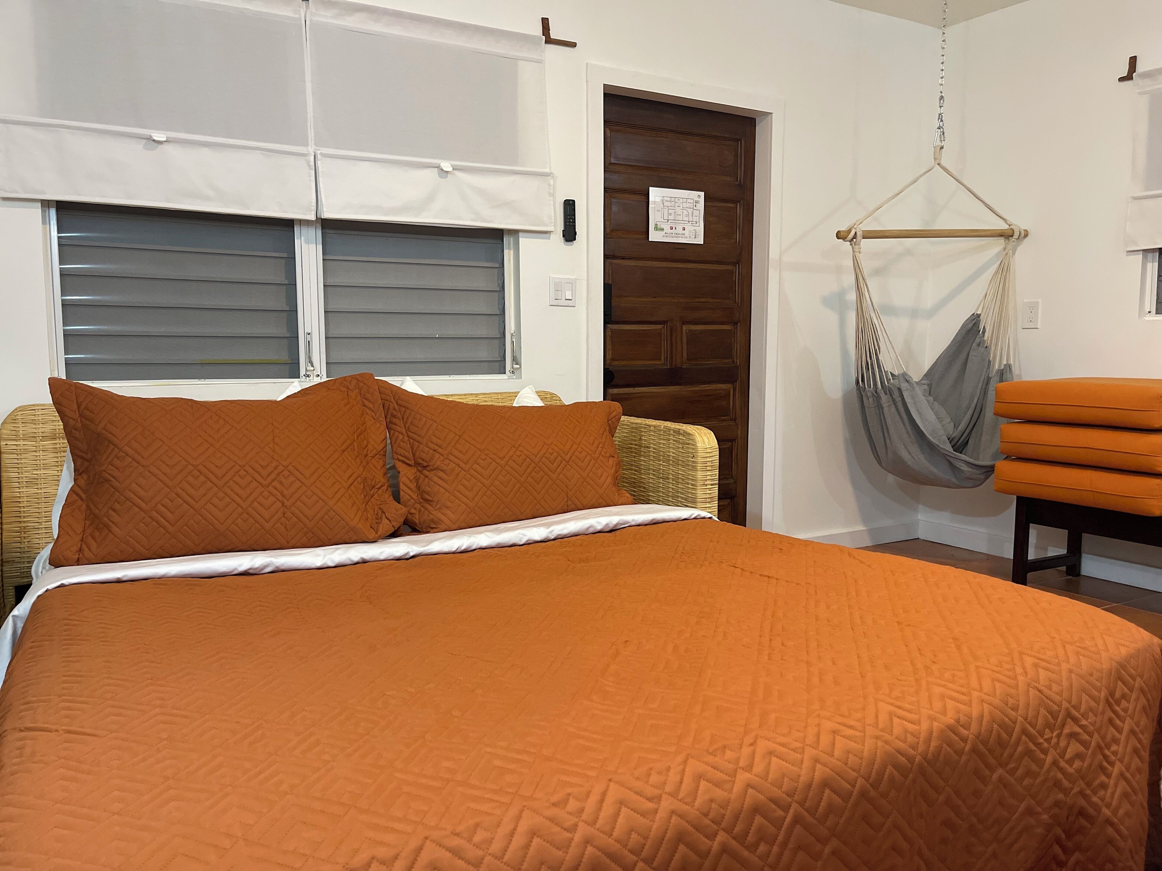 Een slaapkamer met een bed, een hangmat en een deur met een kaart.