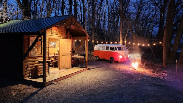A wooden cabin with a dining area and a van parked outside.