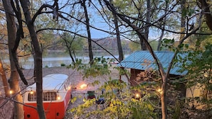 A rustic cabin with a metal roof, surrounded by trees and a lake.