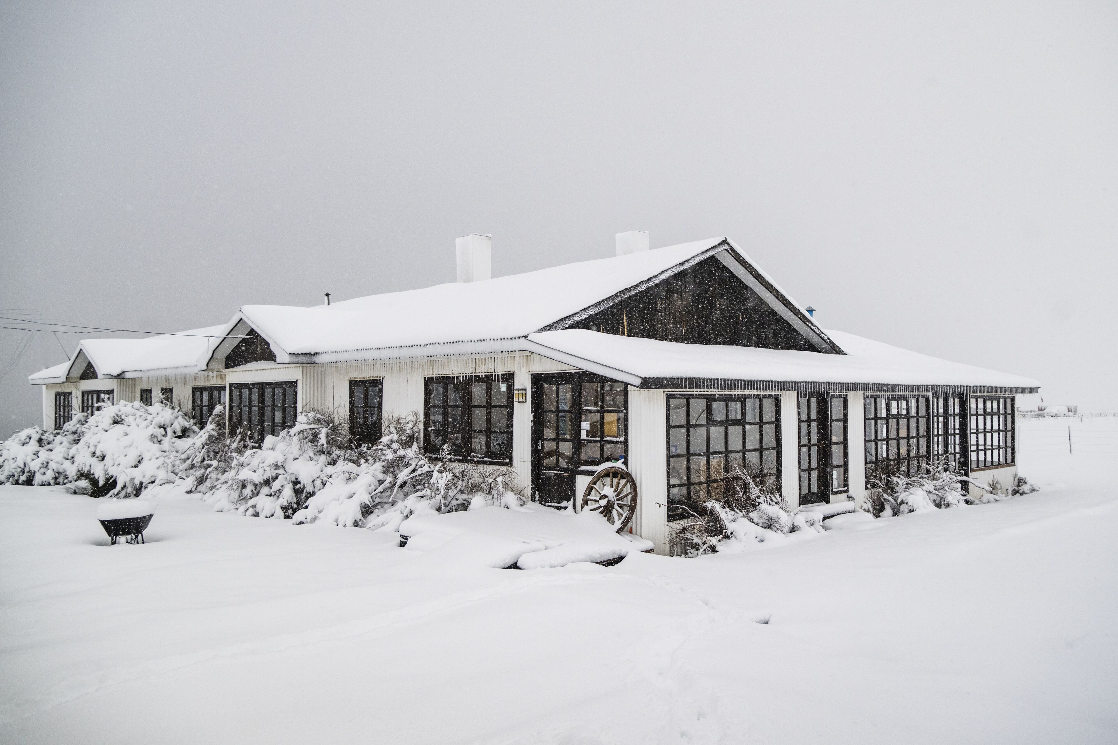 A snow-covered building with large windows and a covered porch area.