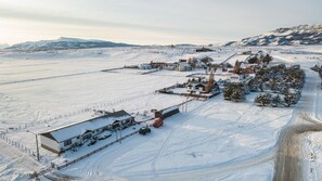 A snow-covered landscape with a large building complex, including a main house and several smaller structures, surrounded by open fields and distant mountains. - BORIES - Boutique Guest House (Natales)