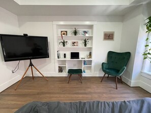 Relax in this stylish living room with a flat-screen TV, comfortable chair, and shelving unit.
