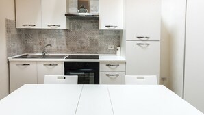 A modern kitchen with white cabinets, a stainless steel sink, and patterned backsplash tiles. - S311 - Sirolo, new two-room apartment completely renovated (Sirolo)