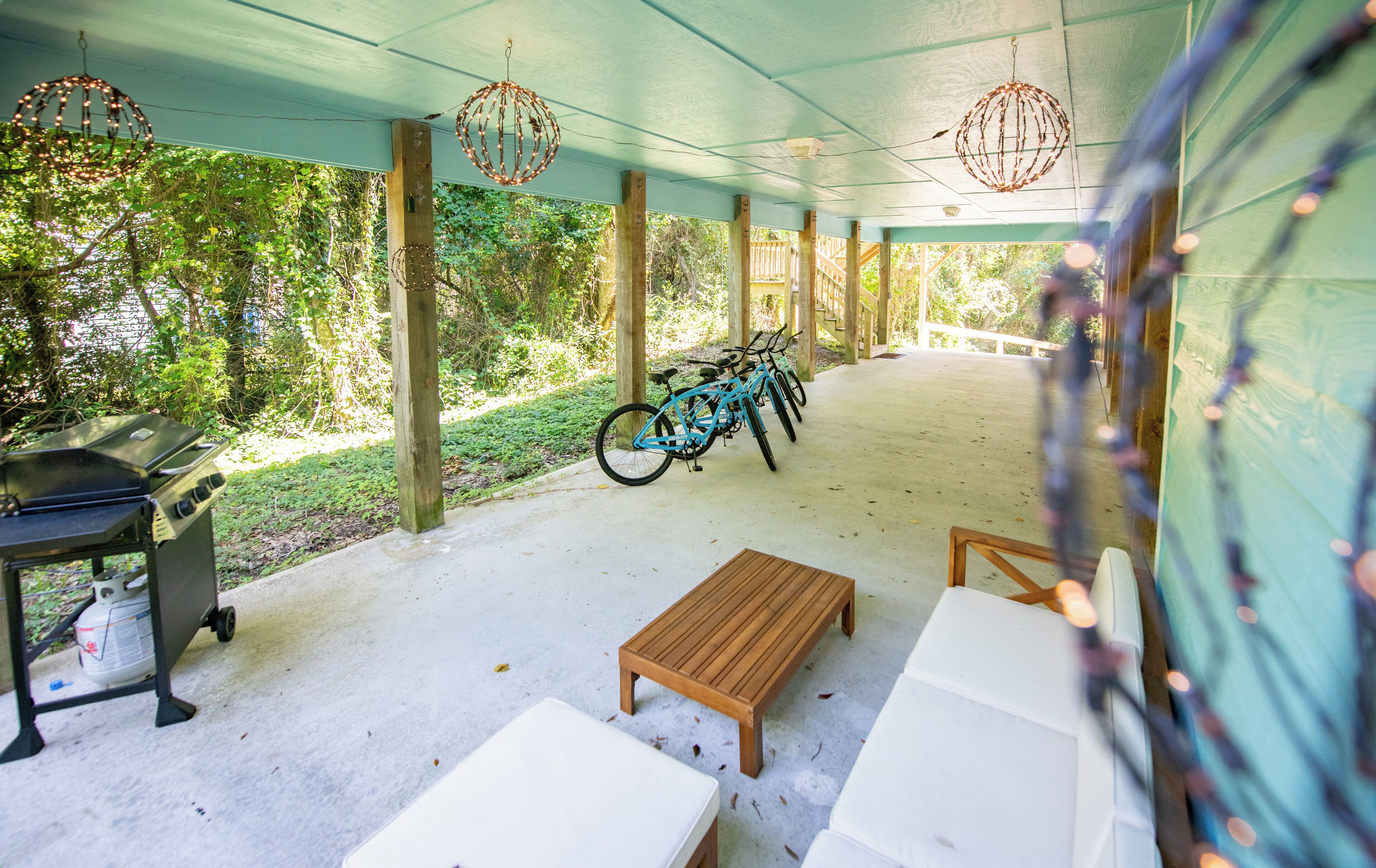 Eine überdachte Terrasse im Freien mit Grill, Fahrrad und Holzbank.