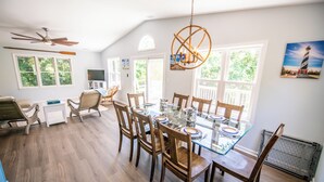 A dining area with a glass table, wooden chairs, and a ceiling fan.
