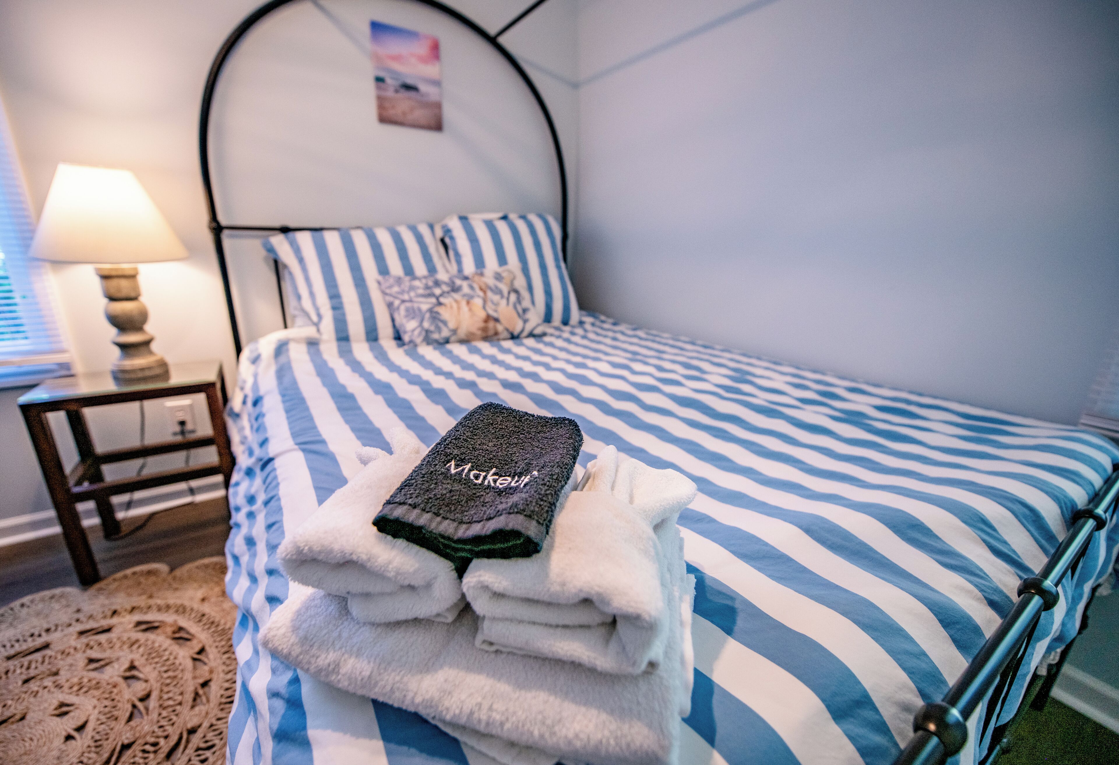 Un lit bien fait, avec une literie à rayures et une serviette pliée posée sur le dessus.