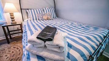 Un lit bien fait, avec une literie à rayures et une serviette pliée posée sur le dessus.