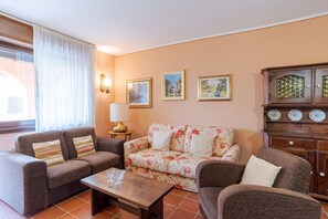 A living room with a sofa, armchairs, a coffee table, and a cabinet with decorative plates.
