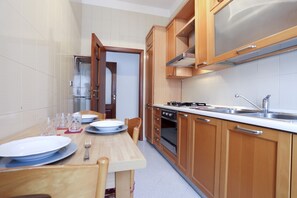 A compact kitchen with wooden cabinets, a stove, and a sink.